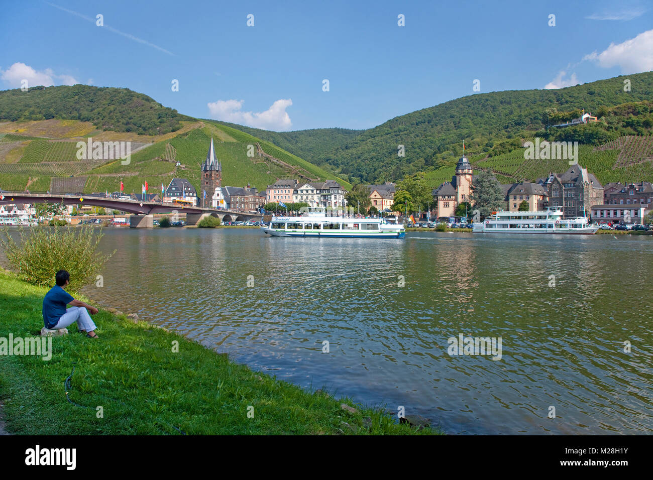 Woman sits at riverside and watch excursion ships on Moselle river, Bernkastel-Kues, Moselle river, Rhineland-Palatinate, Germany, Europe Stock Photo