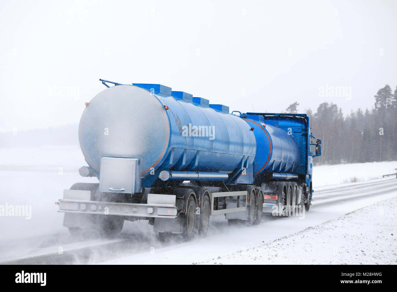 SALO, FINLAND - FEBRUARY 3, 2018: Blue Scania tank truck moves along snowy highway in snowfall, rear view. Stock Photo