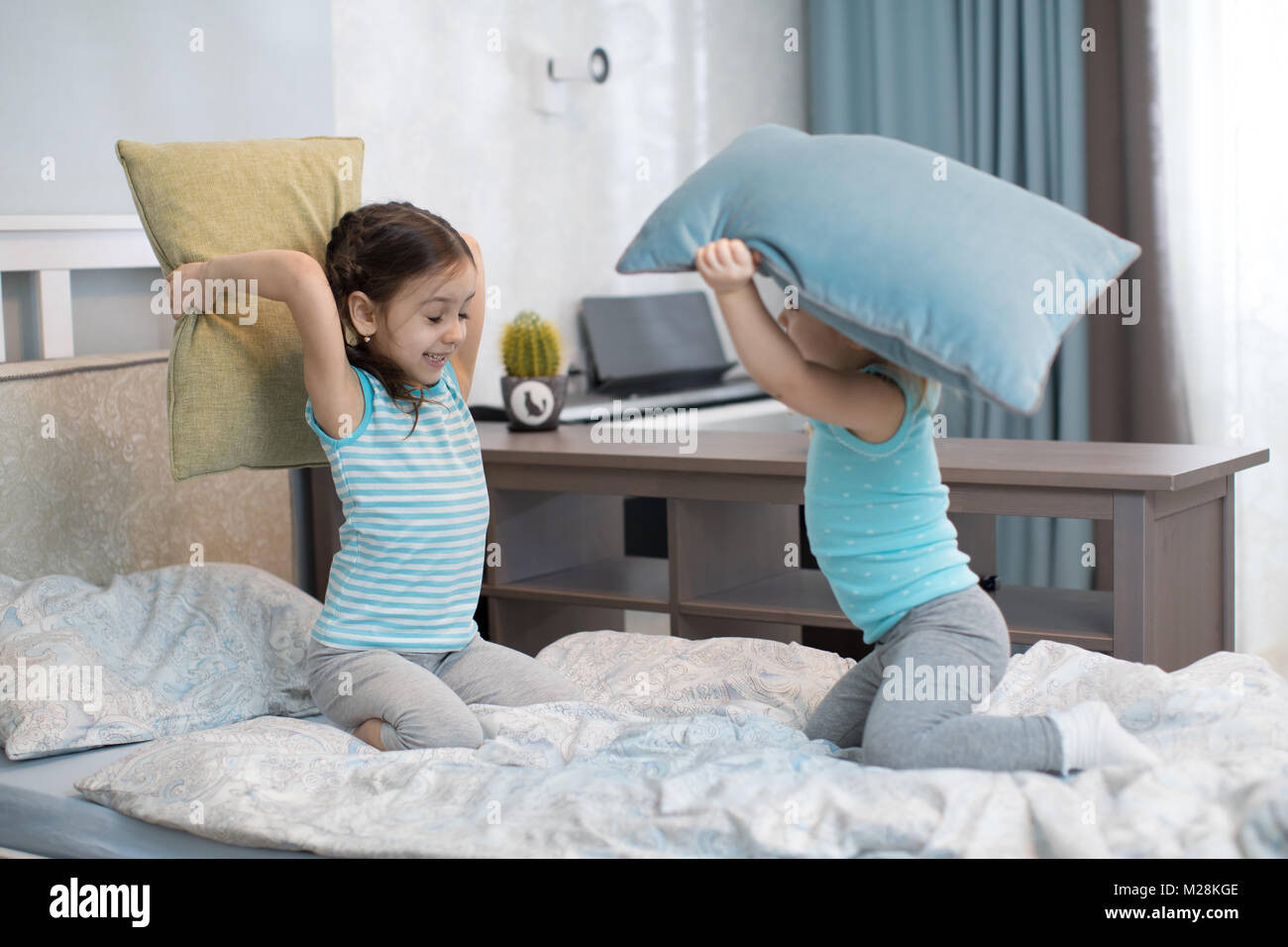 Little children girls fighting using pillows in bedroom Stock Photo