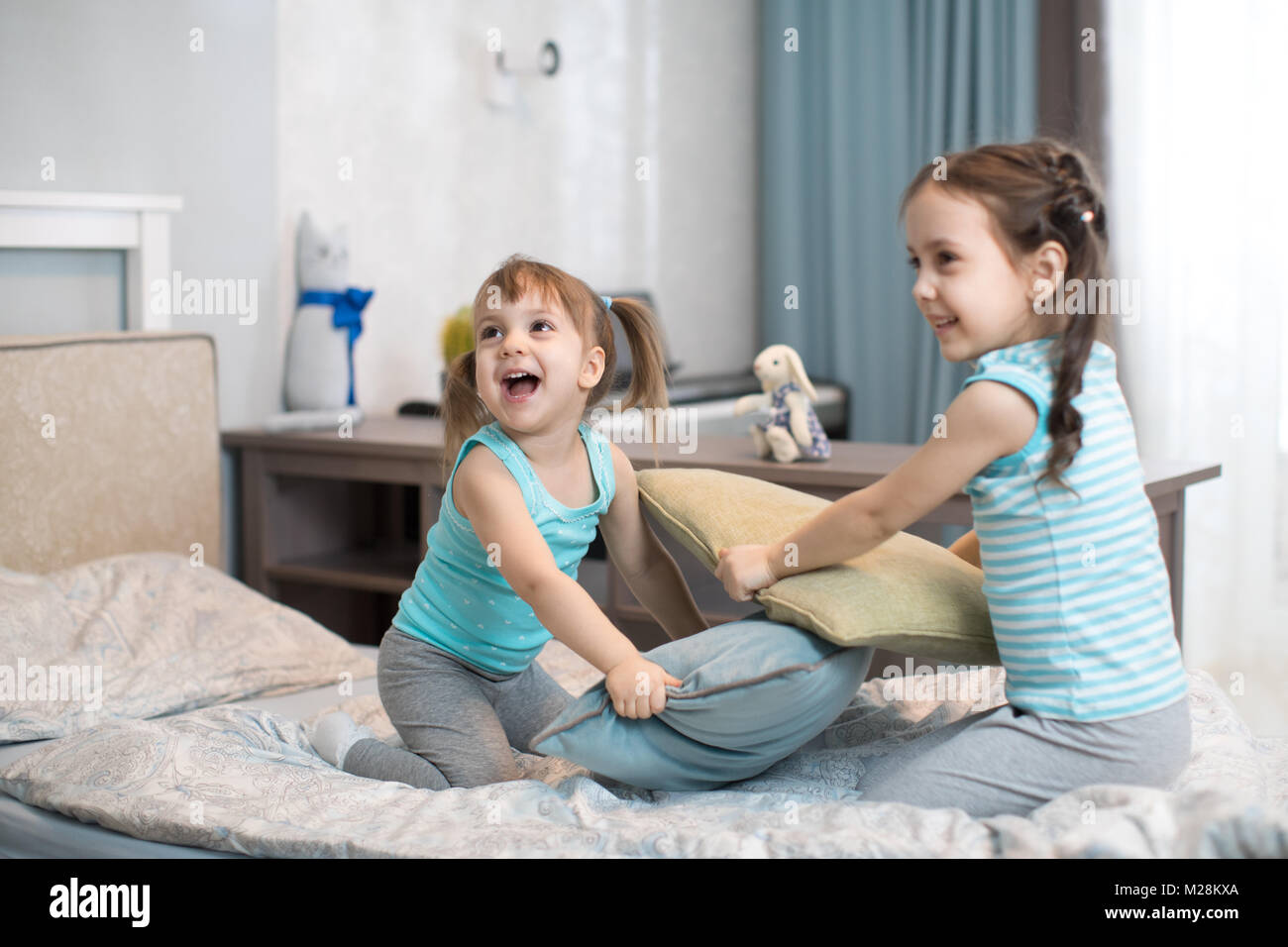 Kids girls fighting using pillows in bedroom Stock Photo