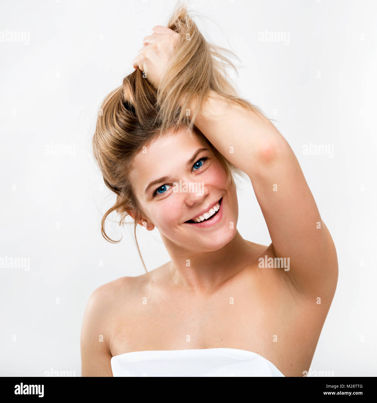 Portrait of a cute smiling young woman on a light background. Female face close-up. The girl demonstrates healthy beautiful hair Stock Photo