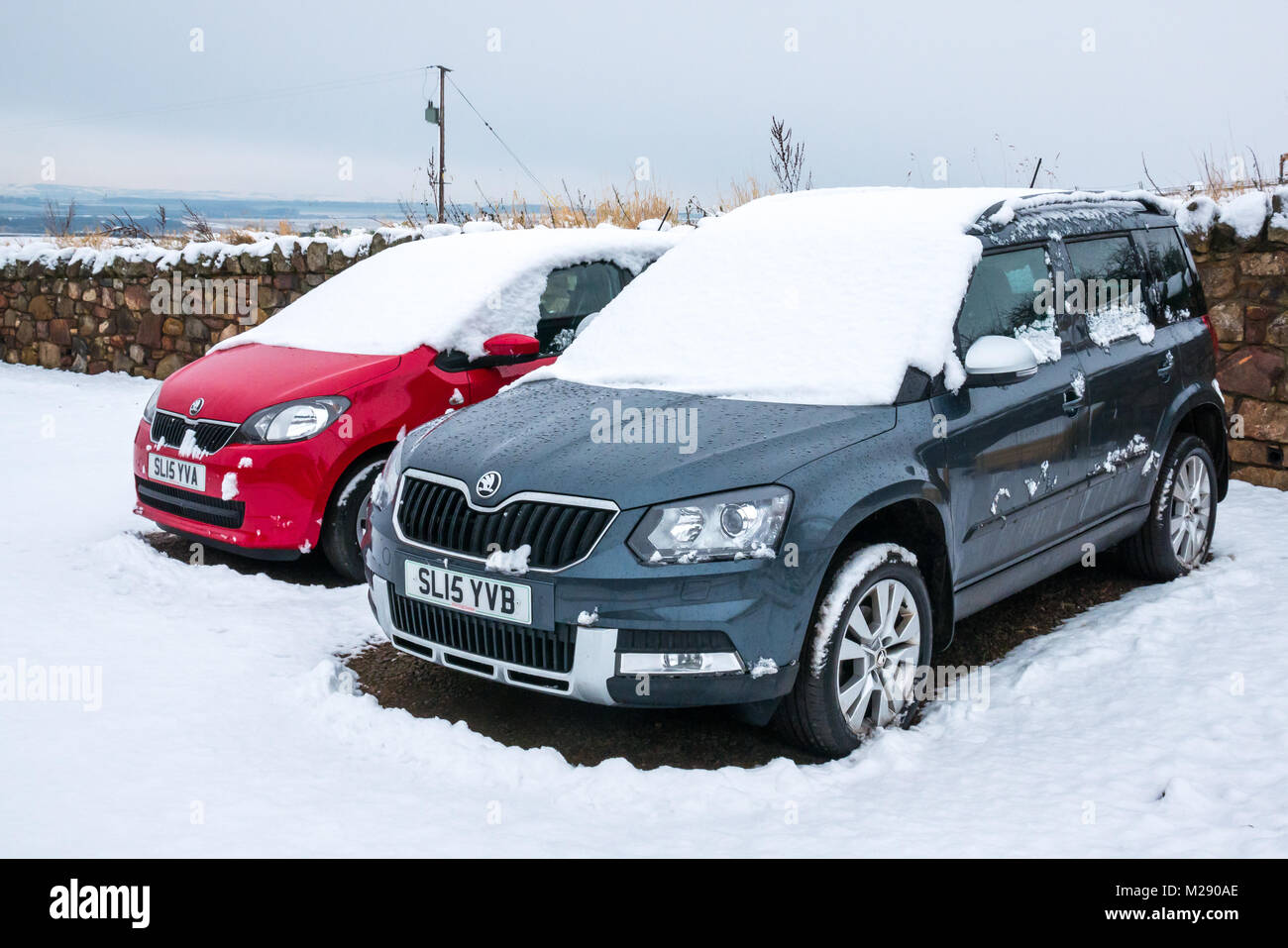 East Lothian, Scotland, United Kingdom.  A cold morning with several inches of snow on cars when owners went out in the morning. A red Skoda Citigo and a blue Skoda 4x4  Yeti, with matching number plates Stock Photo