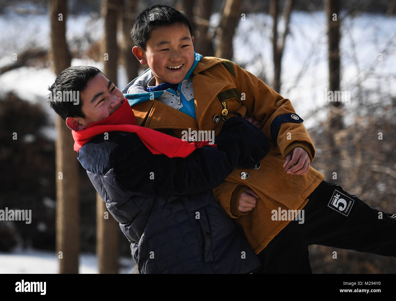 (180206) -- KANGLE, Feb. 6, 2018 (Xinhua) -- Sun Jianjun (L) and his younger brother Sun Jianqiang play in Xinzhuang Village, Basong Township, Kangle County of northwest China's Gansu Province, Feb. 3, 2018. Spring Festival, or Chinese Lunar New Year, falls on Feb. 16 this year. Hundreds of millions of Chinese will return to their hometowns for family gatherings. 14-year-old Sun Jianjun and his 15 schoolmates are among these travellers eager back to home. On Feb. 1, the first day of the 2018 Spring Festival travel rush, they stepped onto a train in Nantong of east China's Jiangsu Province Stock Photo