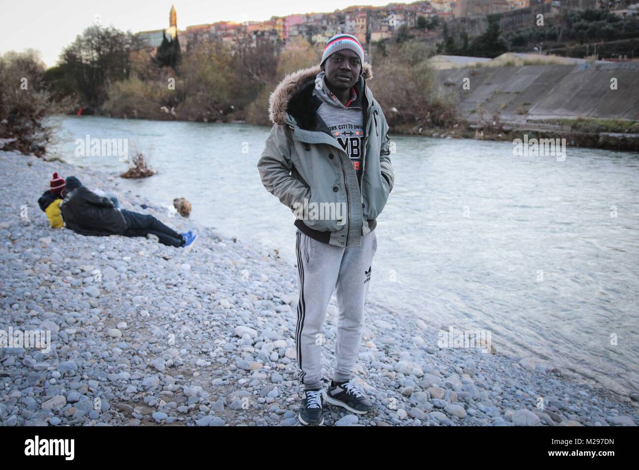 Venitmiglia, Imperia, Italy. 13th Dec, 2017. Salah Baker Alam, from Darfur in Sudan, stands by the river that runs through Ventimiglia. He washes here and sleeps rough beneath a nearby underpass. Hundreds of migrants and refugees are using the Italian town as a base from which to attempt a crossing into nearby France. Most efforts end in failure.Italy is a country hit hard by the European refugee/migrant crisis. Unlike Greece where most of the migrants are from the war torn middle east, most of the migrants in Italy are from African nations heading to Europe for economical reasons. (Cred Stock Photo
