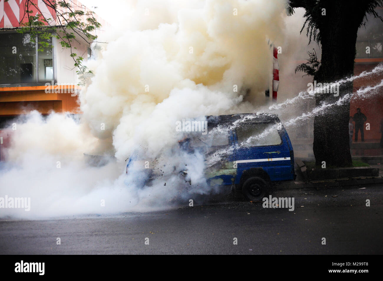 Bogor, West Java, Indonesia, 3 February 2018. Police officers extinguished the fire on a car that was burned by demonstrators during a simulation of the security of local elections, Bogor, West Java, Indonesia, 3 February 2018 Stock Photo