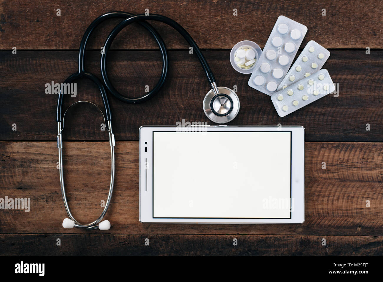 stethoscope, digital tablet and medicine on wooden table background ...