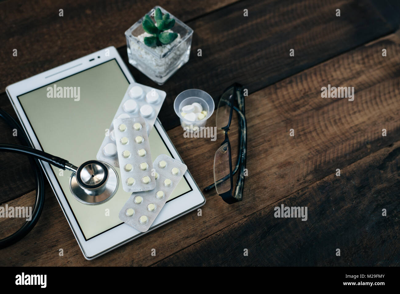 stethoscope, digital tablet and medicine on wooden table background ...