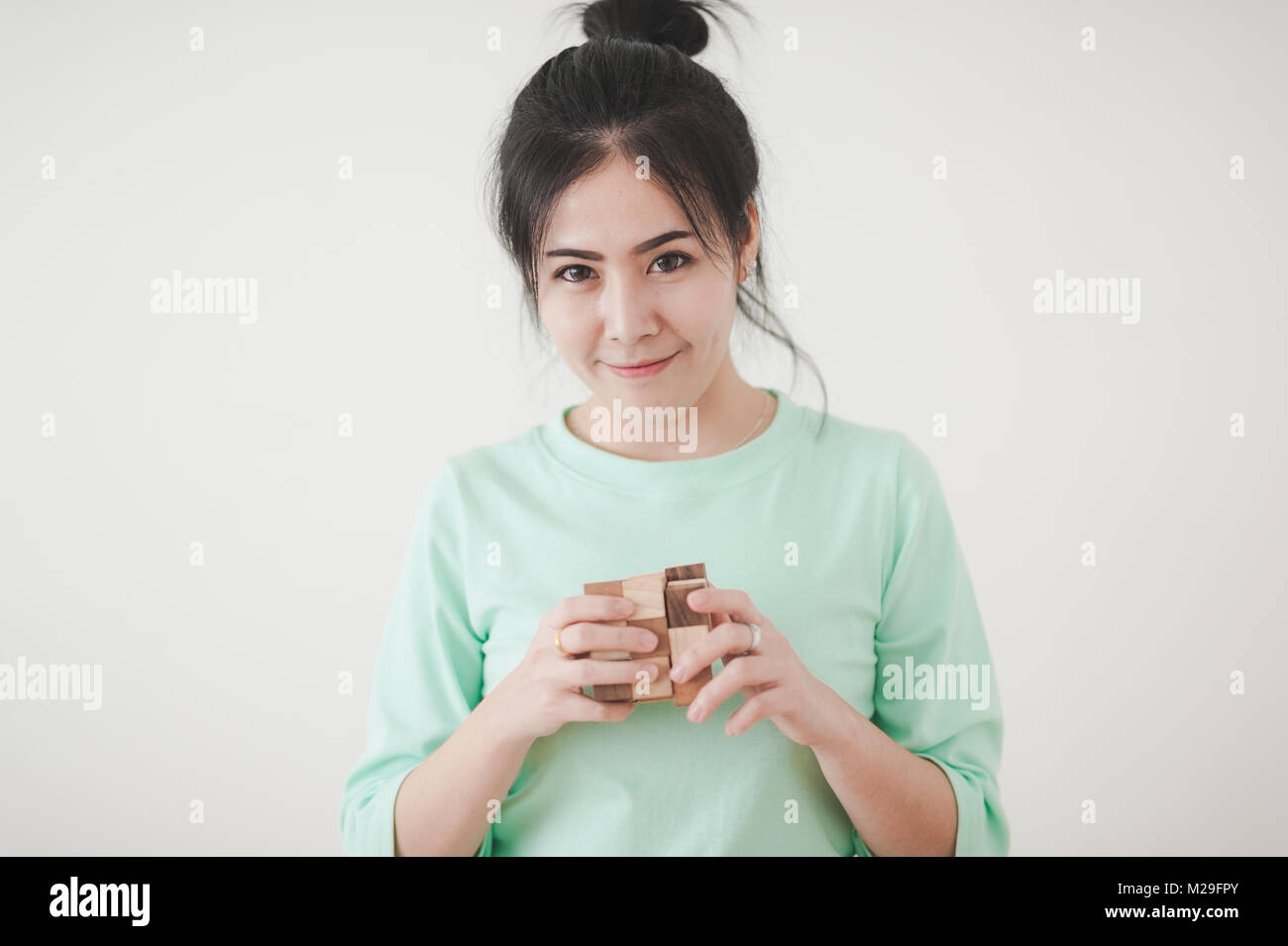 Young Attractive Asian woman wear green shirt playing wooden rubik's cube with positive emotion. Preblem solving abstract concept Stock Photo