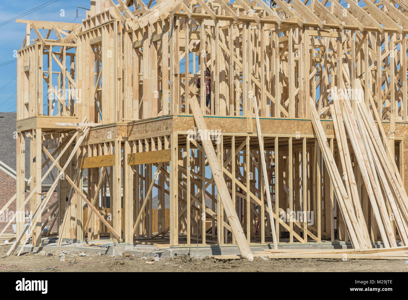 Closeup wood frame house under construction next to completed homes in