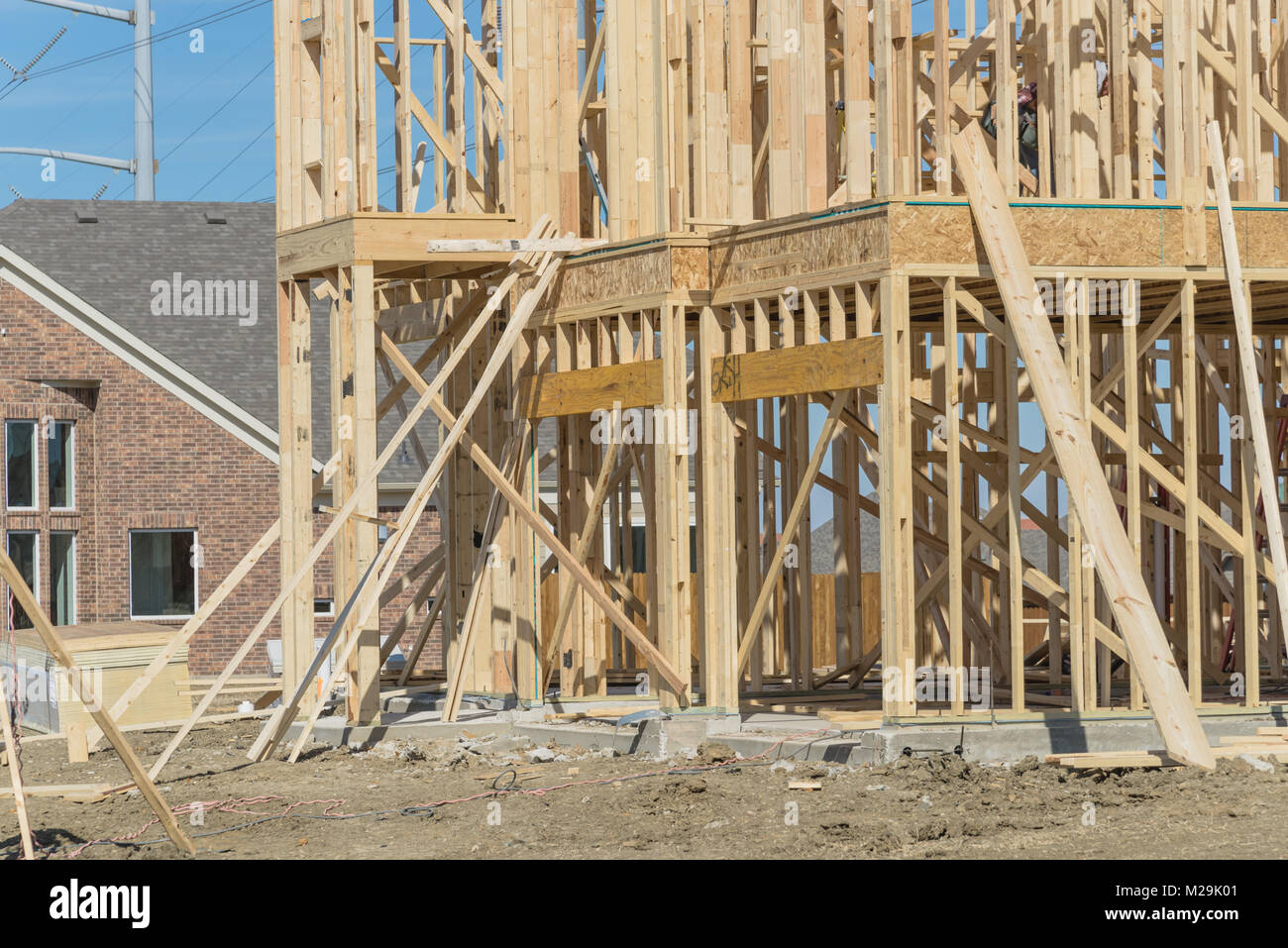 Closeup wood frame house under construction next to completed homes in