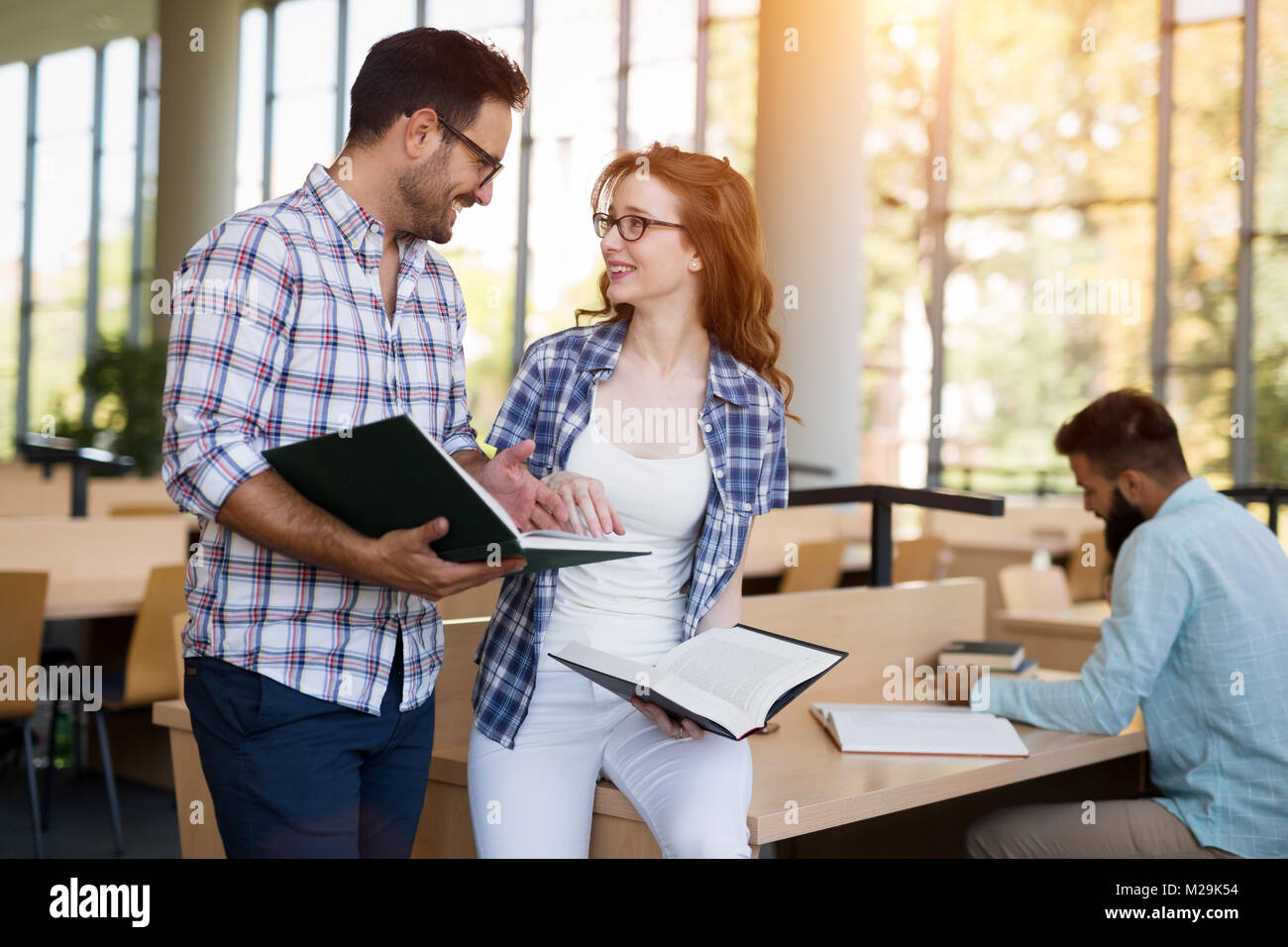 Young happy students sitting in library Stock Photo - Alamy
