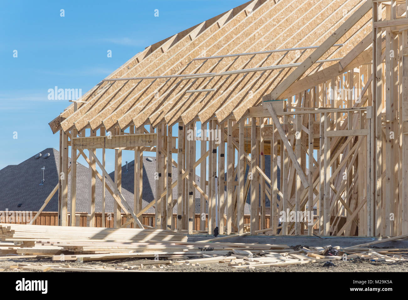 Hilltop wood frame house under construction near completed homes in
