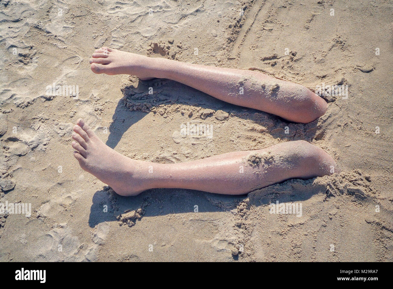 Legs of a boy buried in the sand of a beach, vintage style Stock Photo