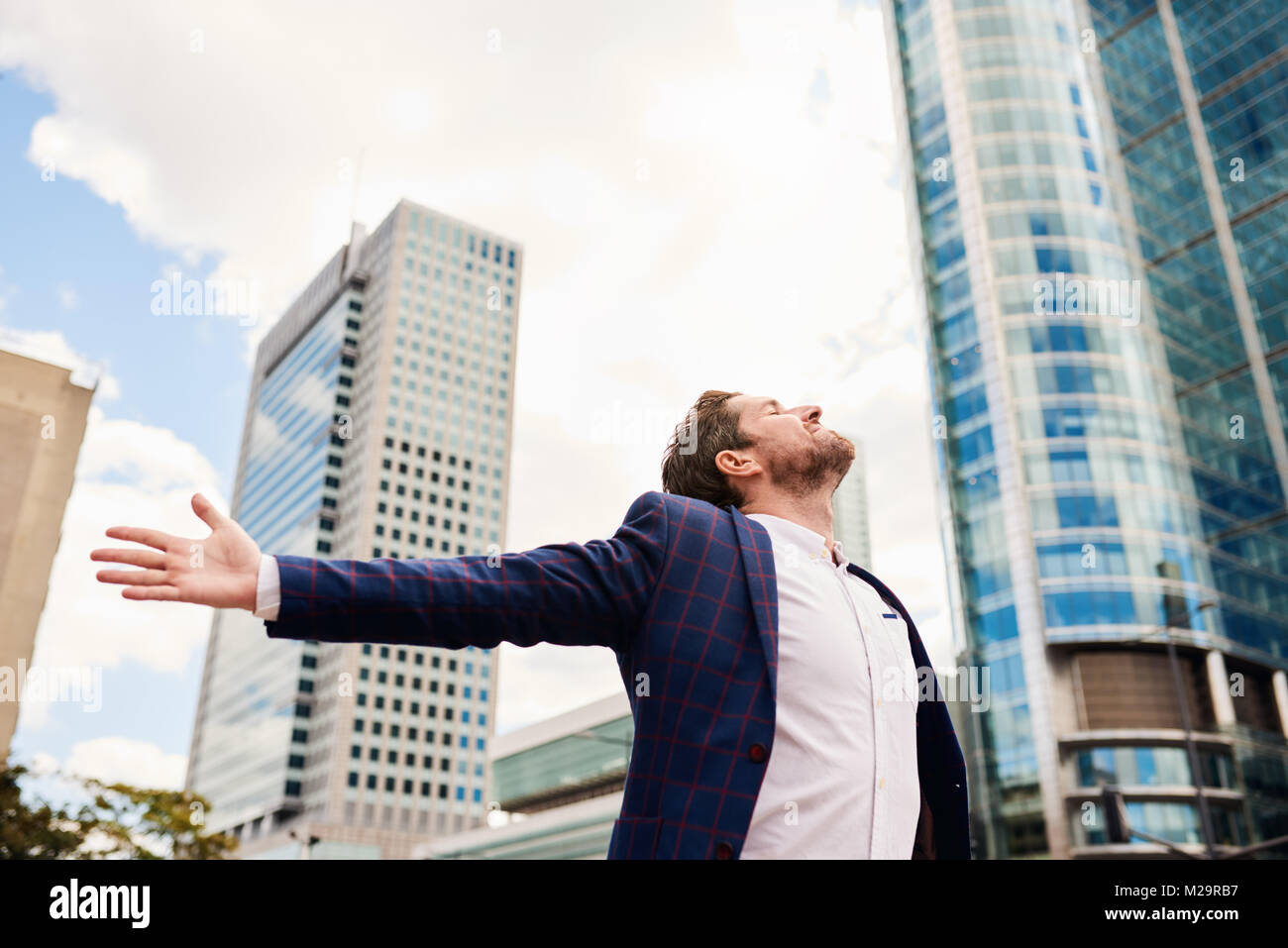 Ambitious young businessman standing in front of office buildings with ...