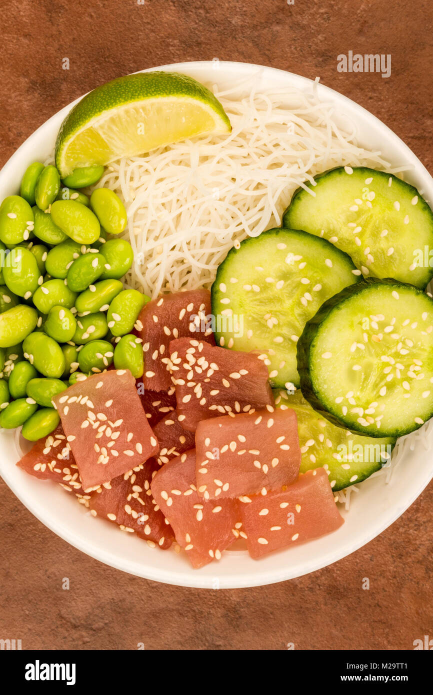 Hawaiian Tuna Fish Poke bowl With Noodles and Edamame Beans Against A Red Background Stock Photo