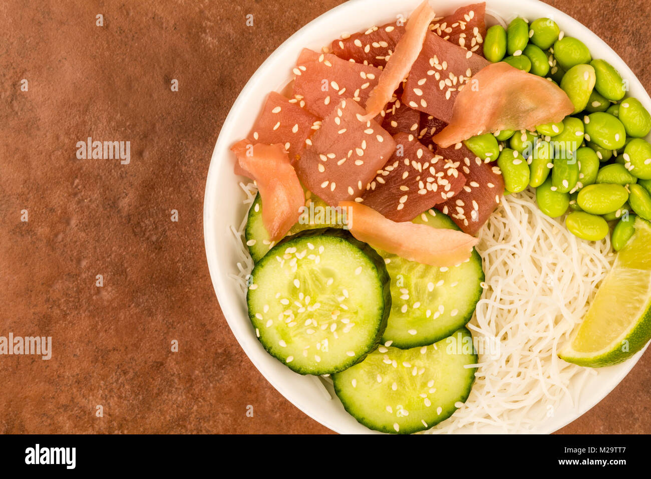 Hawaiian Tuna Fish Poke bowl With Noodles and Edamame Beans Against A Red Background Stock Photo