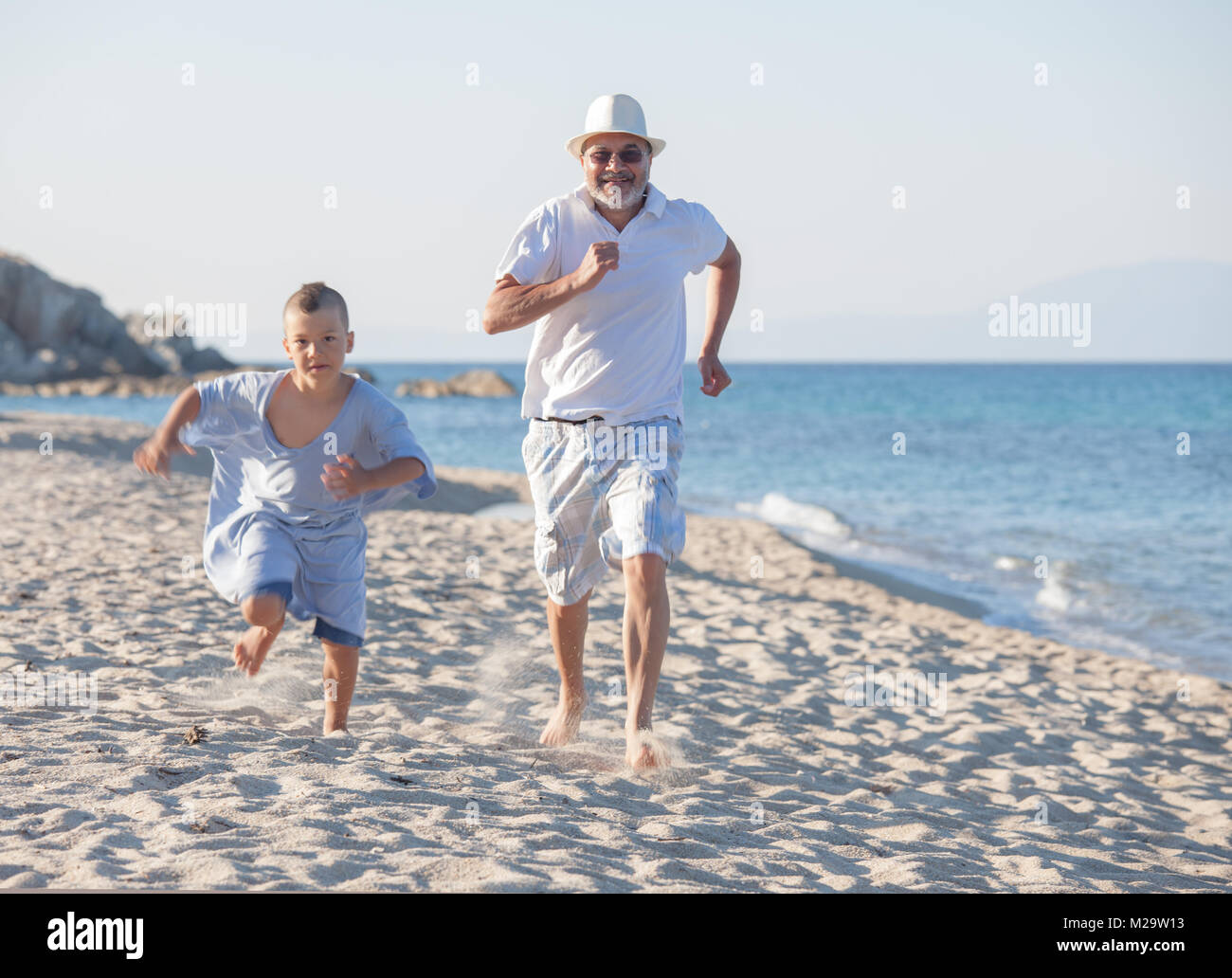 Grandfather racing with his grandson on a quiet empty beach. Stock Photo