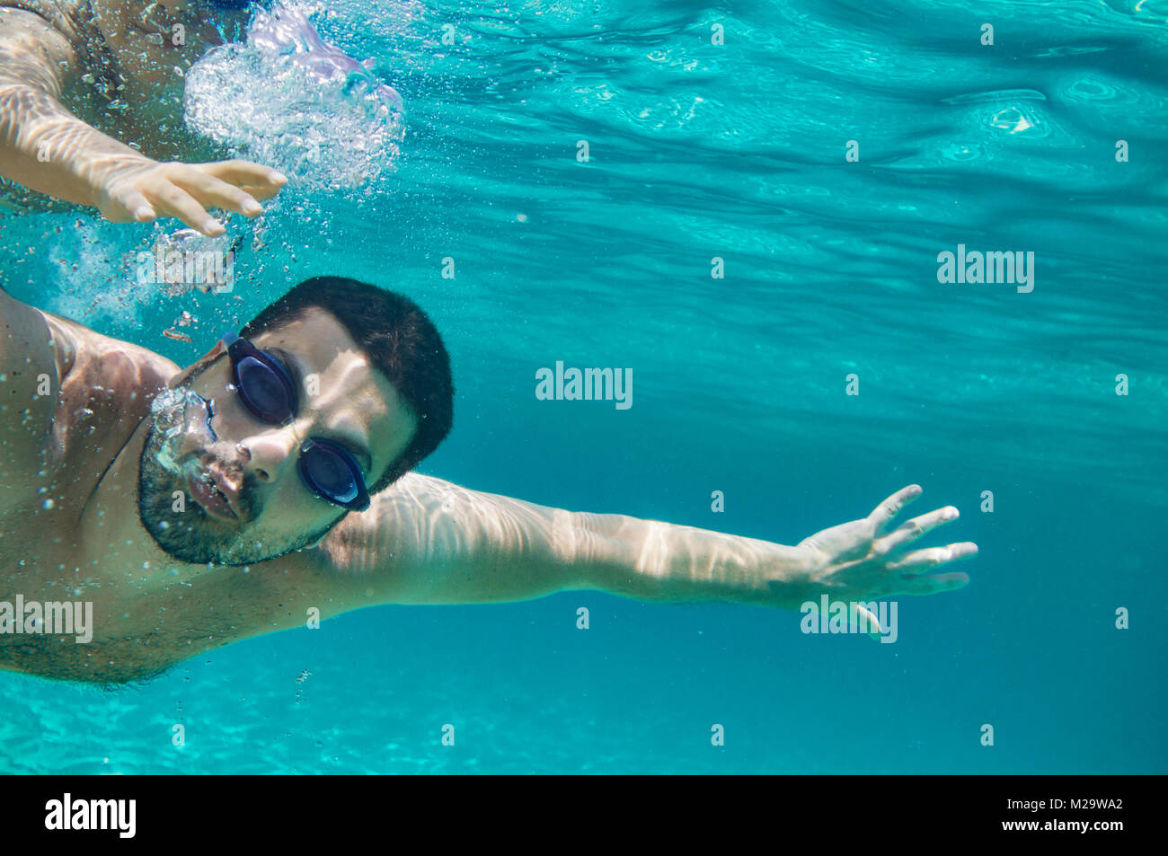 Portrait of young father underwater with his kid around. Stock Photo