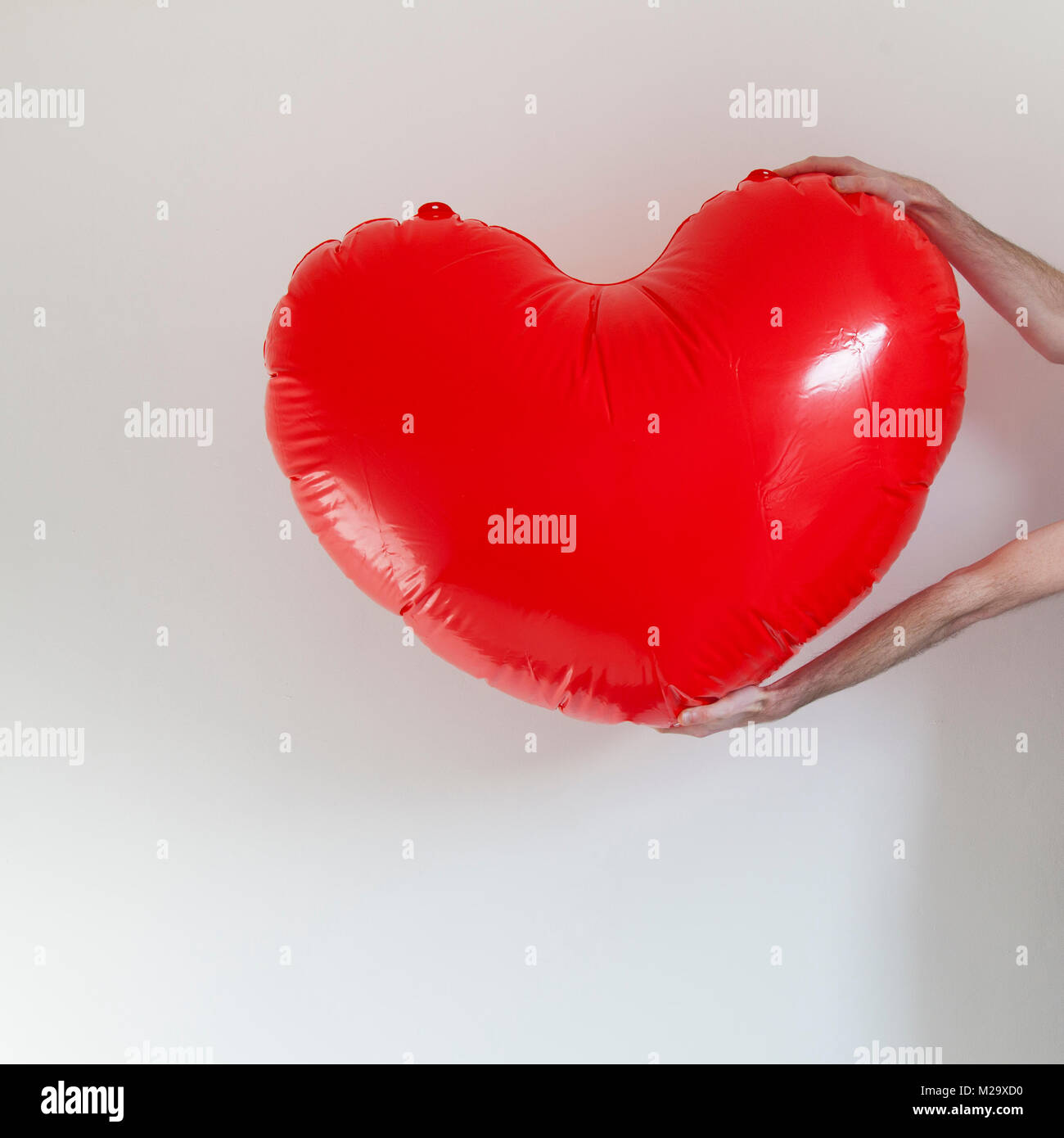 Hands holding a large inflatable heart shape Stock Photo