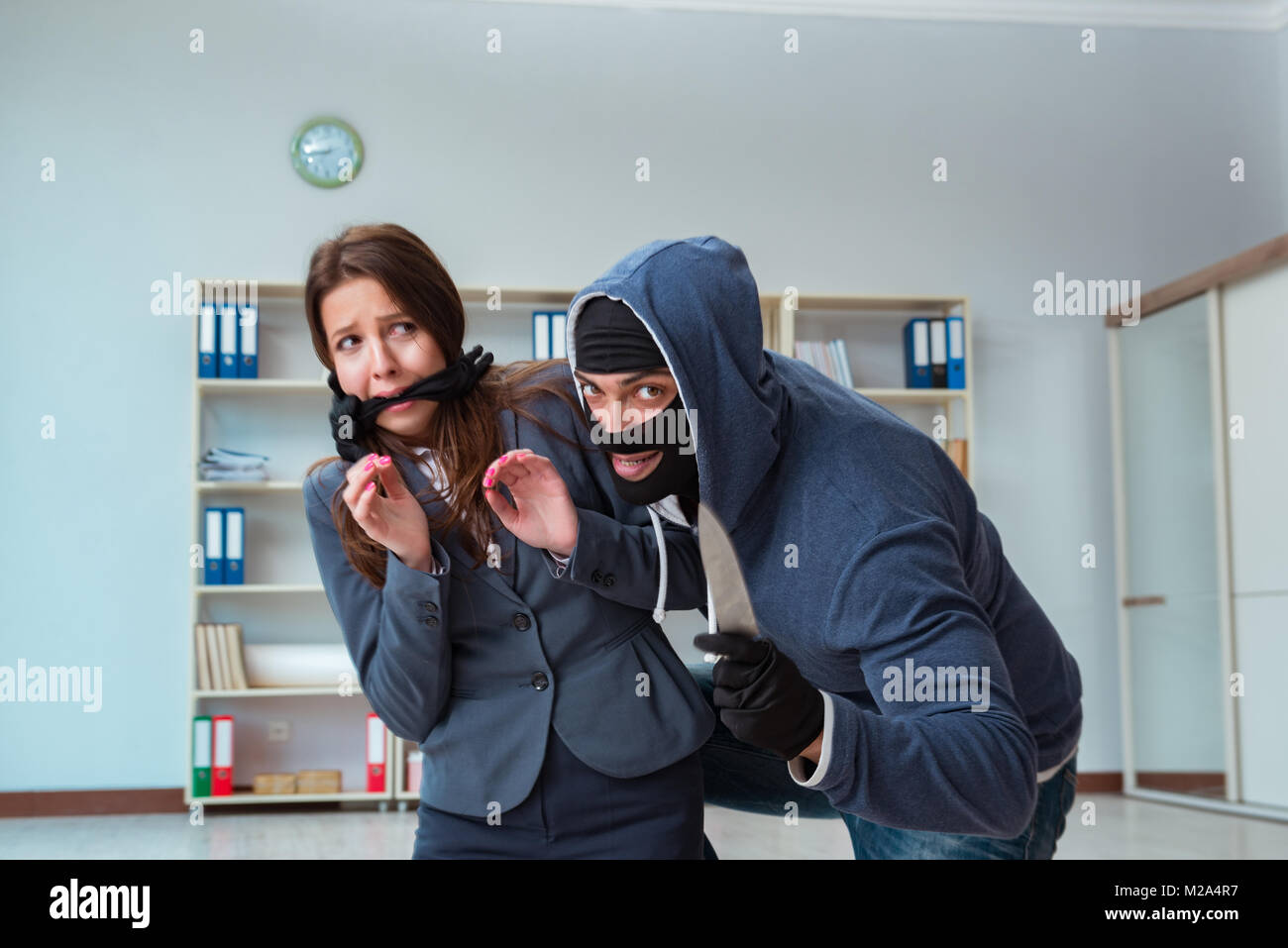 Criminal taking businesswoman as hostage in office Stock Photo - Alamy