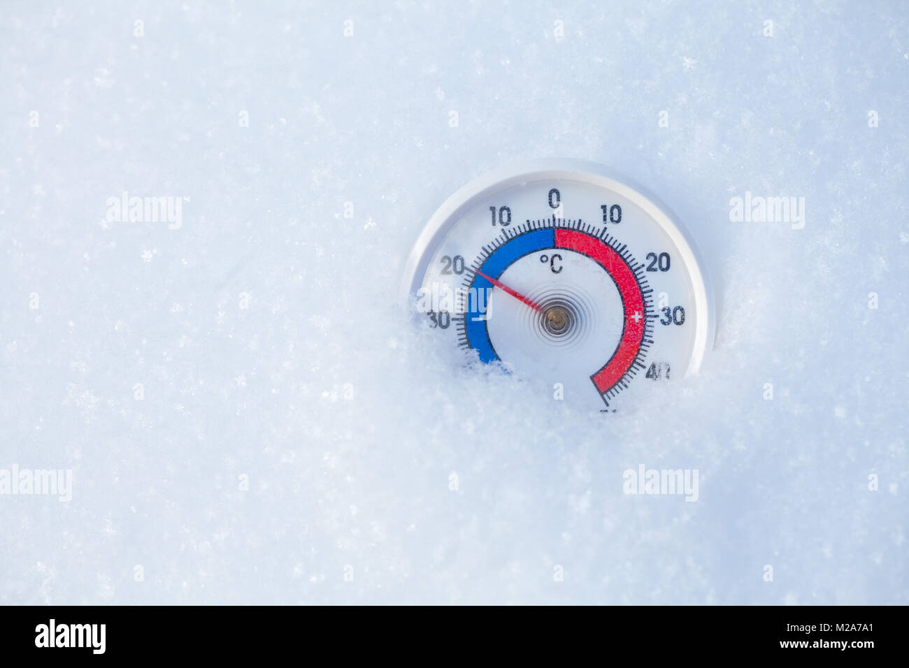 Thermometer with celsius scale placed in a fresh snow showing sub-zero temperature minus 20 degree - cold winter weather concept Stock Photo