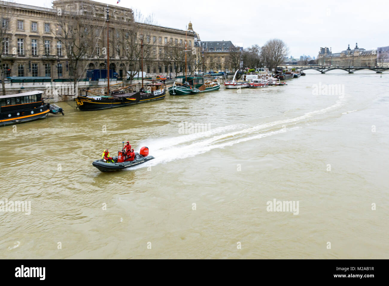 Paris, France - January 29, 2018: Divers from the Paris Fire Brigade, very busy during the flooding of the Seine, go up the river at full speed on a b Stock Photo