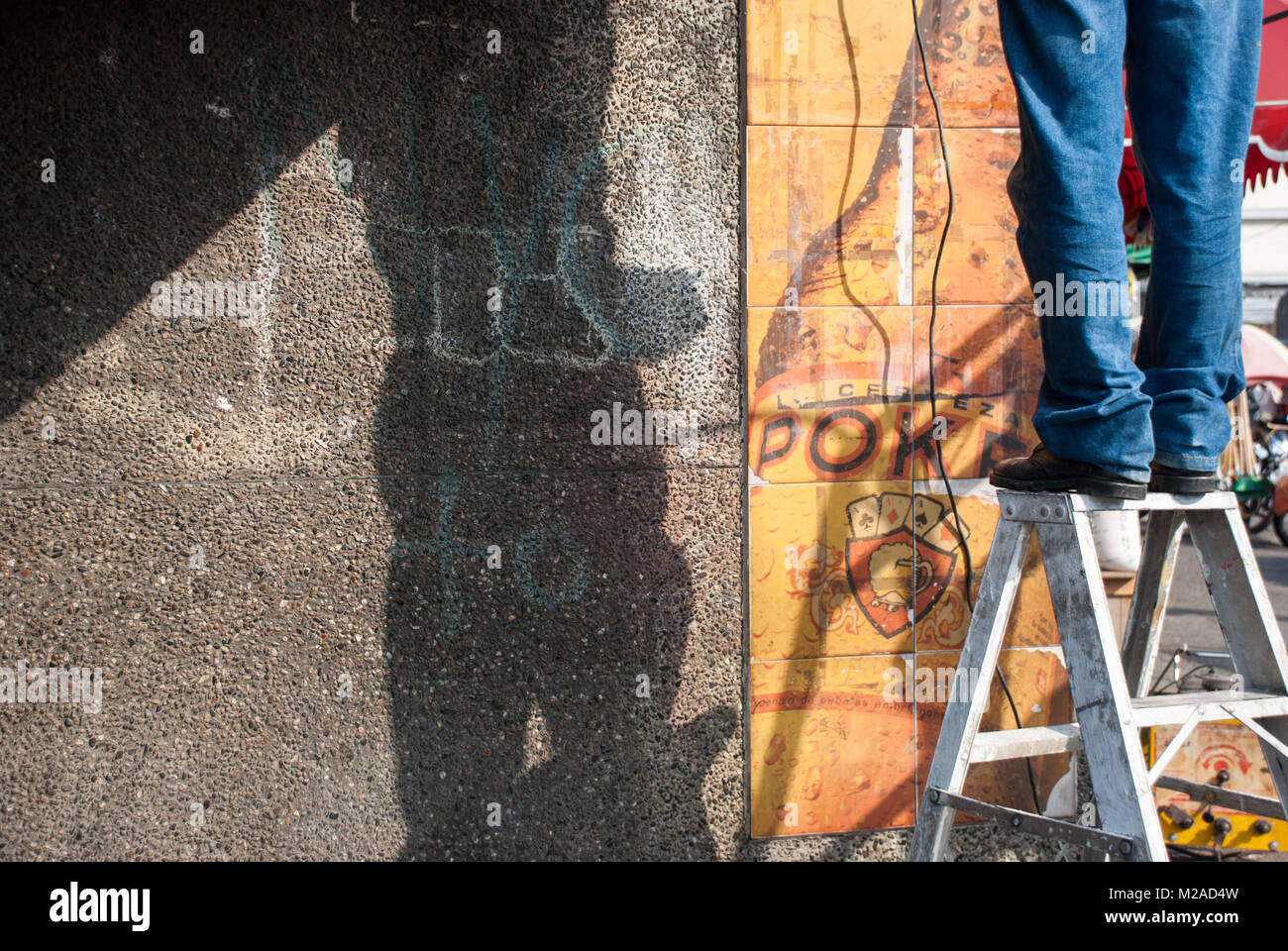 A man standing on a stepladder wearing jeans while repairing wiring Stock Photo