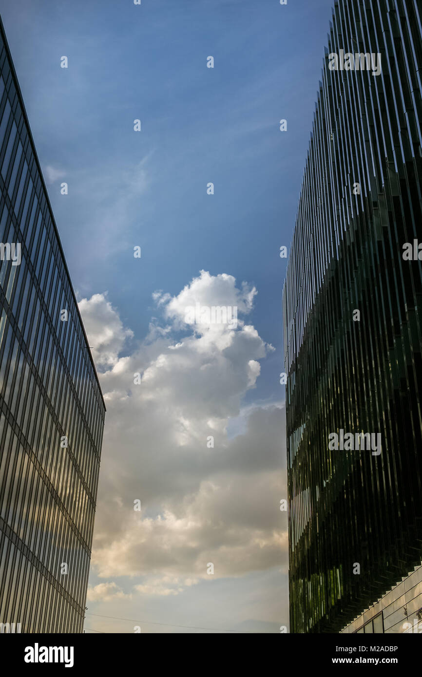 The clearance between two large modern buildings, and is seen the blue sky with clouds in it. Stock Photo