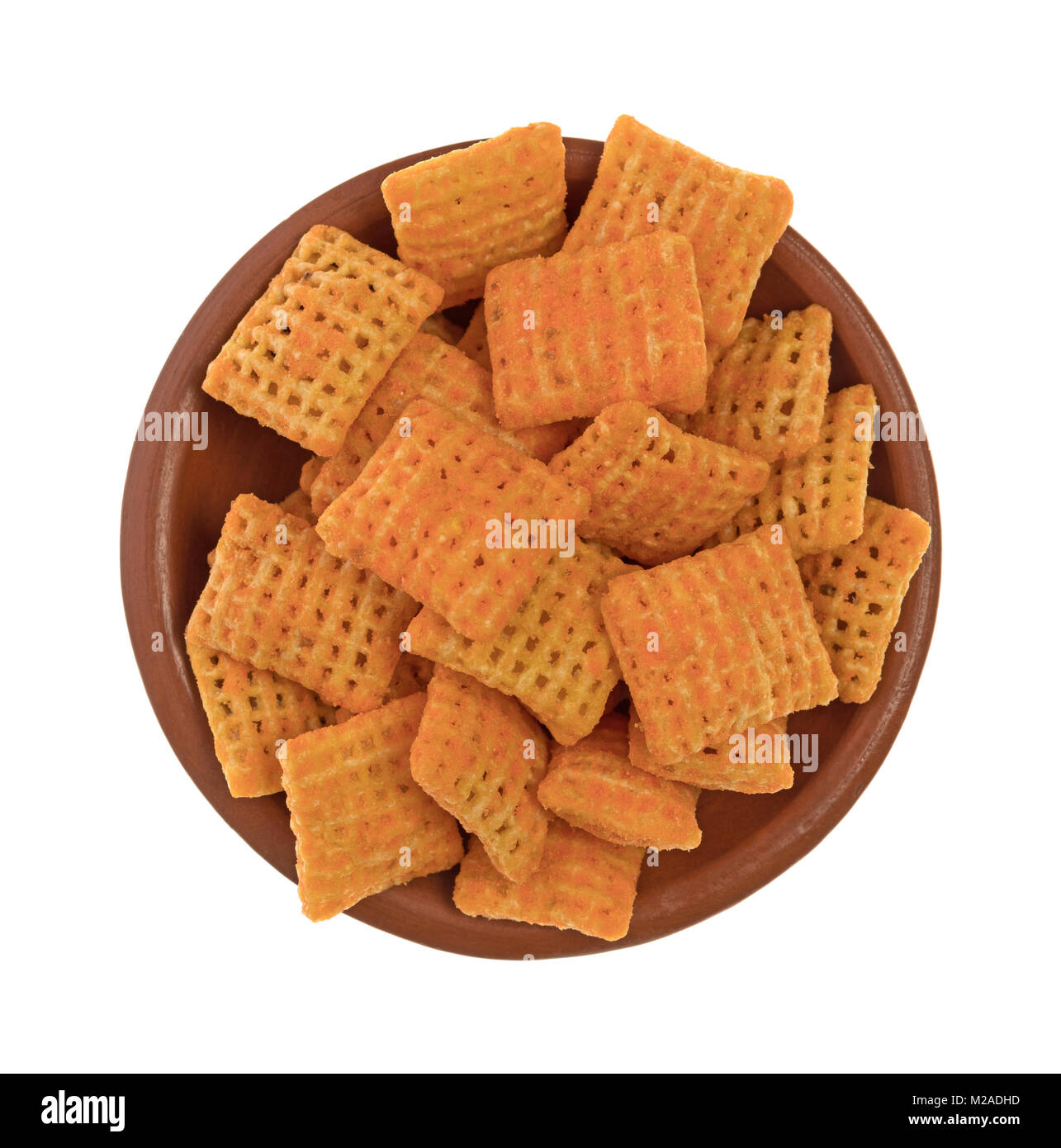 Top view of a small bowl filled with cheddar cheese flavored crispy rice crackers isolated on a white background. Stock Photo