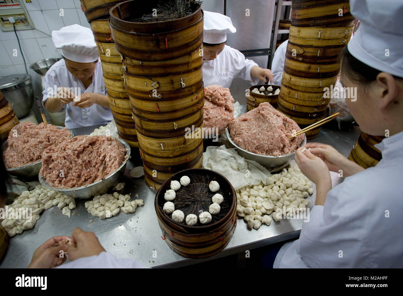 China. Shanghai. Old Town, near Yuyuan Gardens. Women preparing steamed dumplings or dim sum (in steamer baskets). Stock Photo