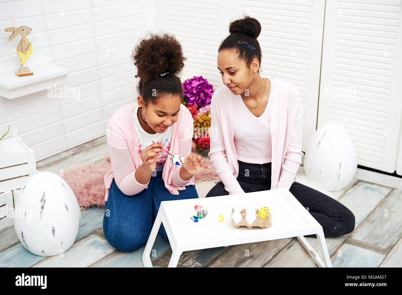 Two girls with black skin paining eggs Stock Photo