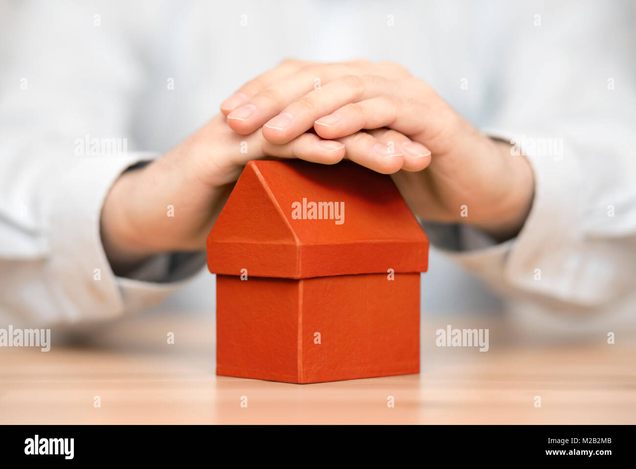 Small orange house protected by hands Stock Photo