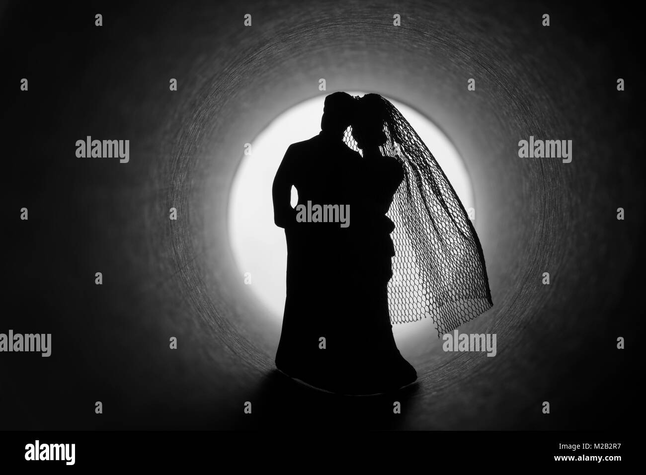 Marriage crisis. Bride and groom figures in a dark tunnel Stock Photo