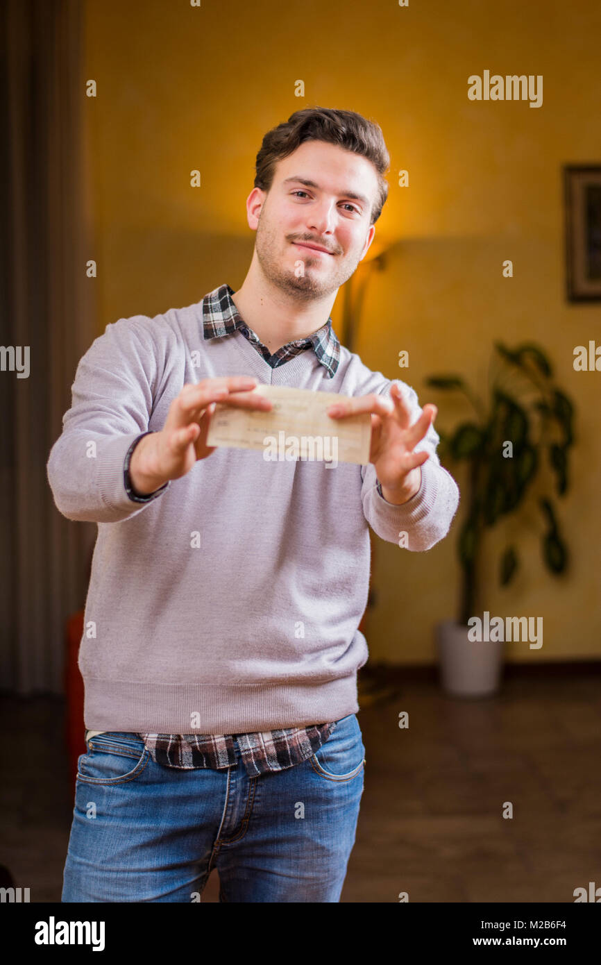 Handsome young man holding check in his hands Stock Photo