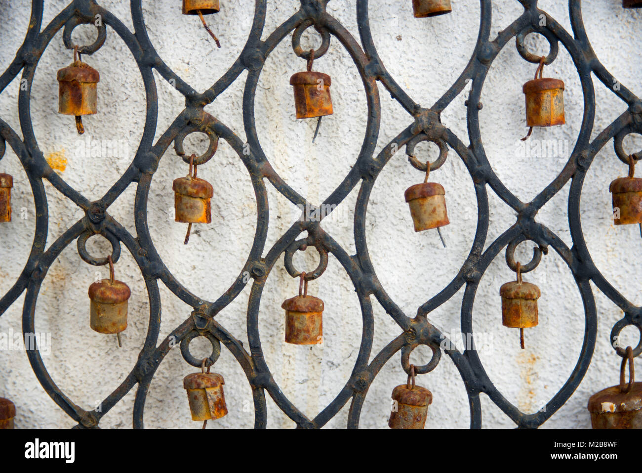 Close up of rusty bells on an ornamental wind chime hanging on a white wall Stock Photo