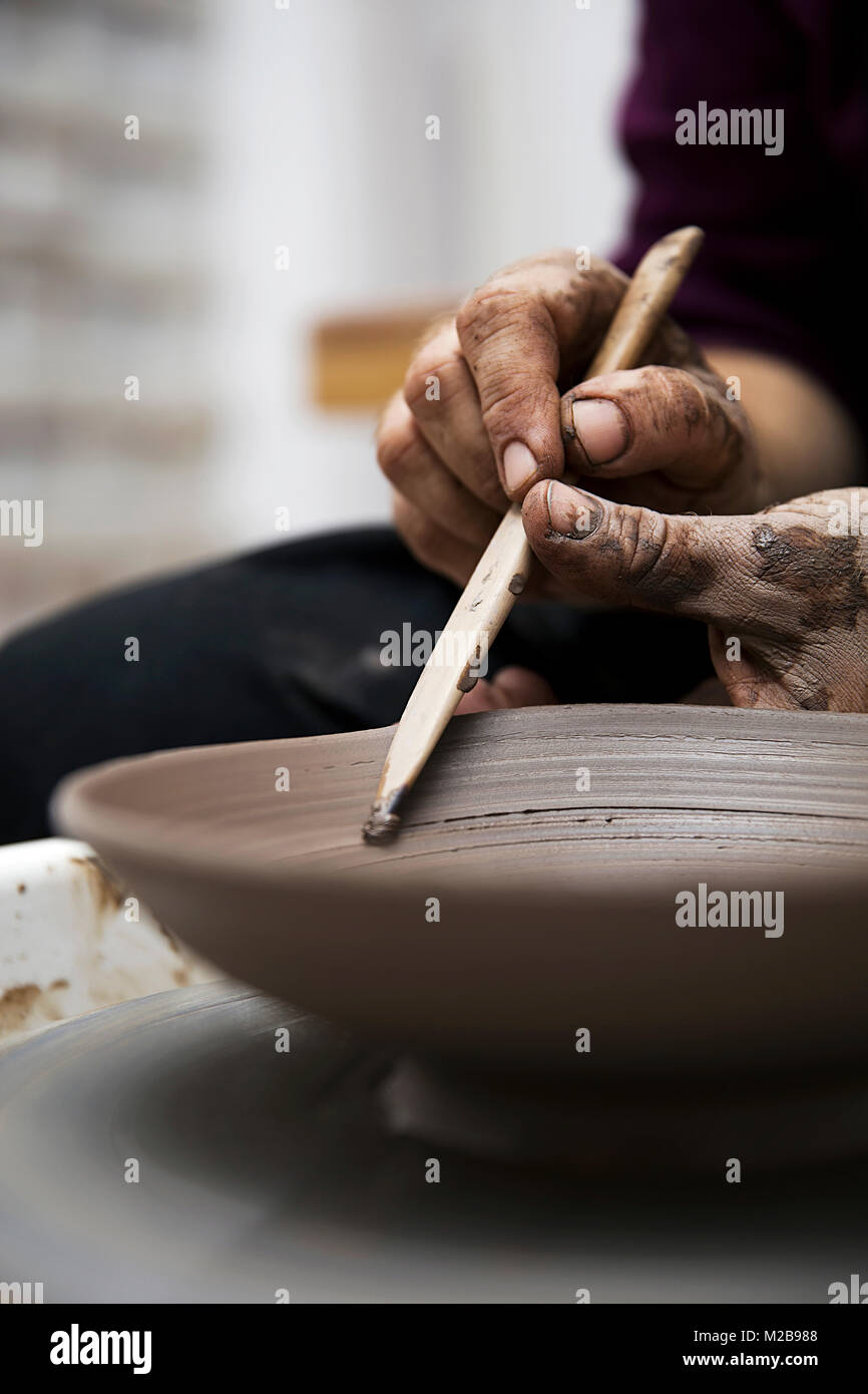 Close up detail view at an artist makes clay pottery on a spin wheel