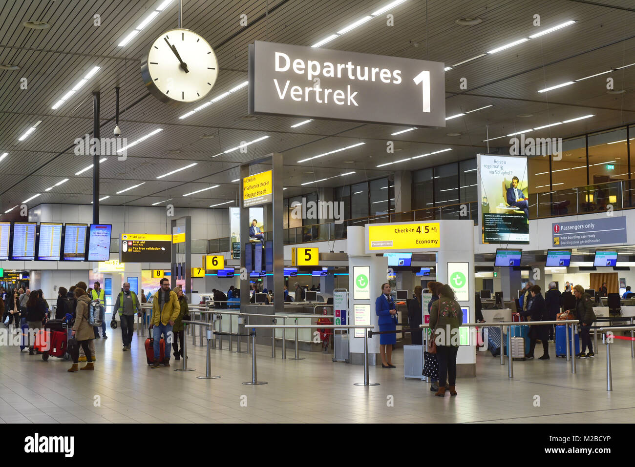 Signs, clock and travellers in departure terminal of Amsterdam Airport Schiphol, Netherlands Stock Photo