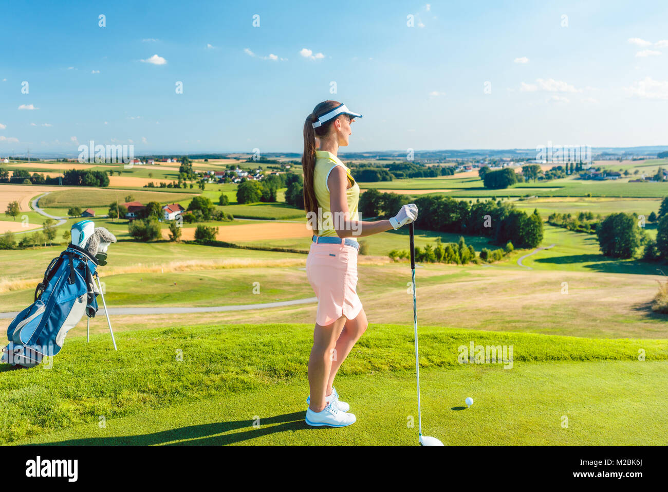 Side view of a fit woman wearing modern golf outfits, while looking at