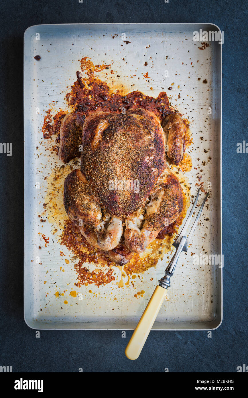 Roast chicken with a herbal crumb on a roasting tray on a slate background. UK Stock Photo