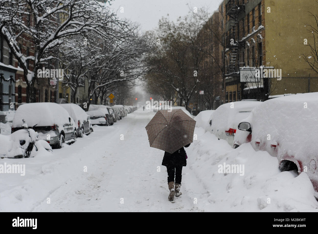 A woman walks threw a snow covered street in New York City after a snowstorm. Stock Photo