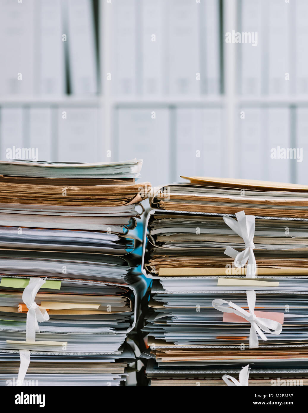 Stacks of files and paperwork in the office and bookshelves on the background: management and storage concept Stock Photo