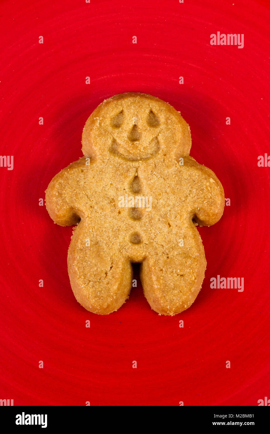 close up of a ginger bread man cookie on a red plate Stock Photo
