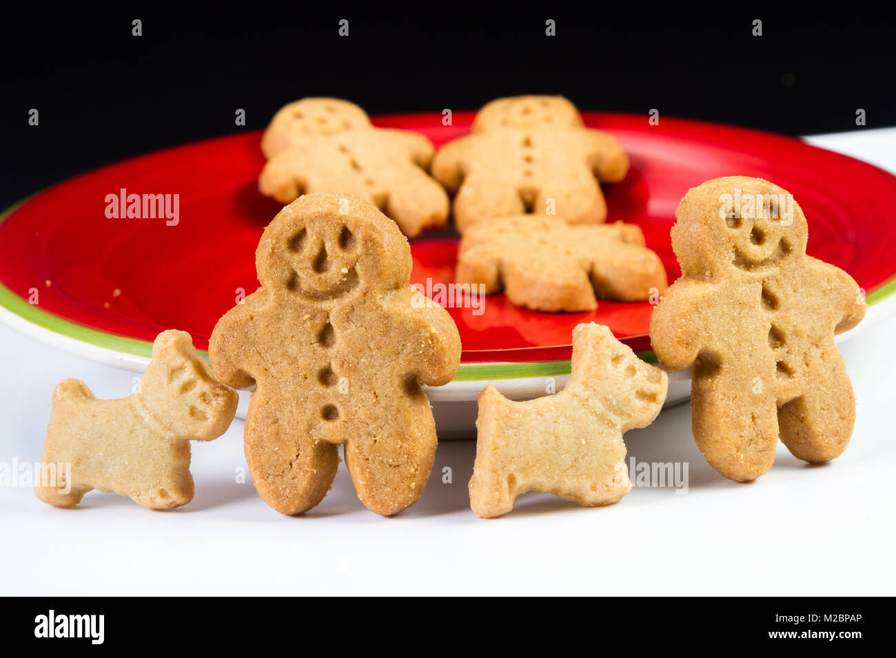 close up of a ginger bread man cookie with his scotty dog on a red plate Stock Photo