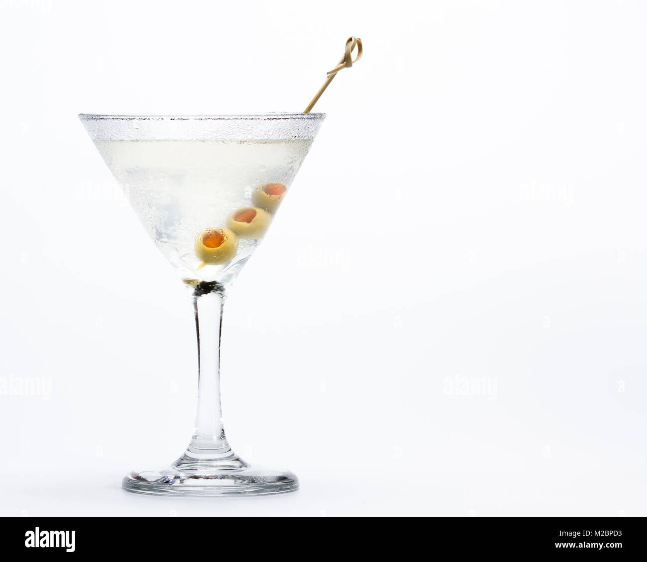 Freshly poured dirty vodka martini with green olives served on a chilled glass isolated on a