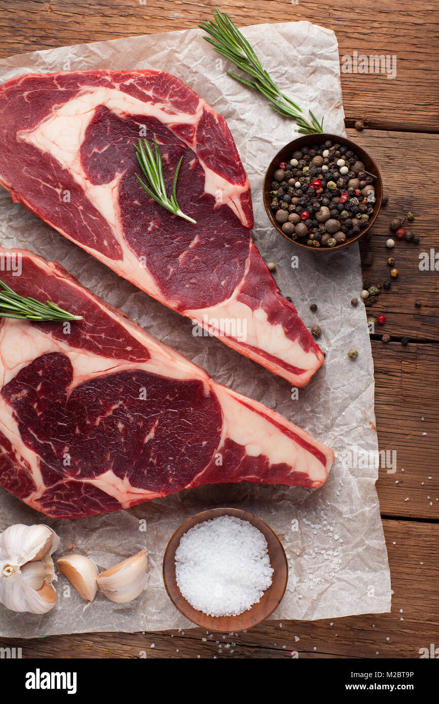 Two fresh raw marble meat, black Angus ribeye steak with spices on a old rustic table. Raw beef on a wooden background. Top view Stock Photo