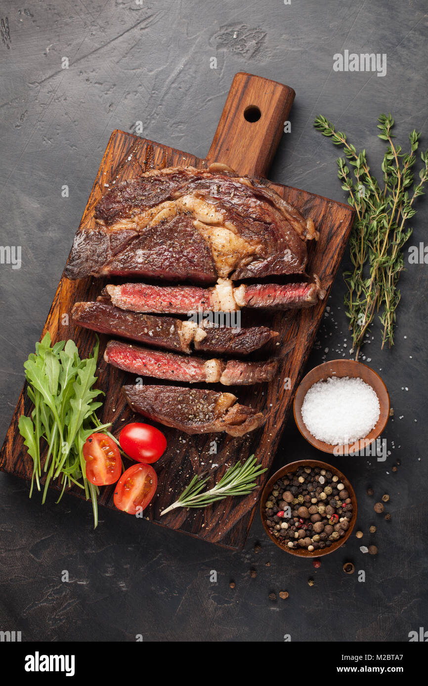 Grilled ribeye beef steak with red wine, herbs and spices on a dark