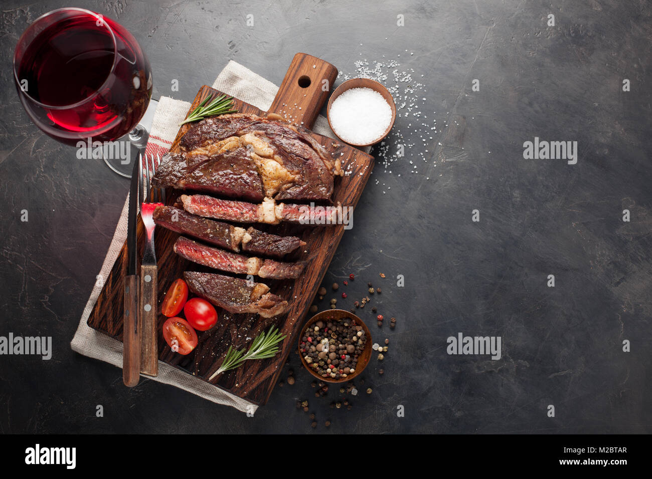 Grilled ribeye beef steak with red wine, herbs and spices on a dark