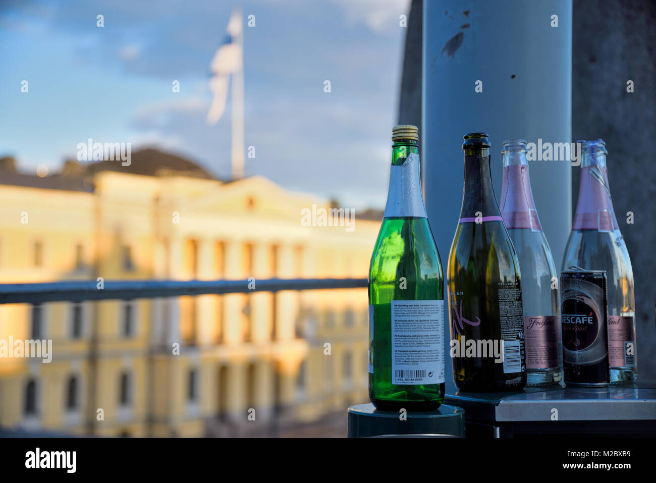 Helsinki, Finland - May 1, 2017: Sparkling wine bottles on top of a bin at the Senate Square with the Finnish Government palace on the background. Stock Photo