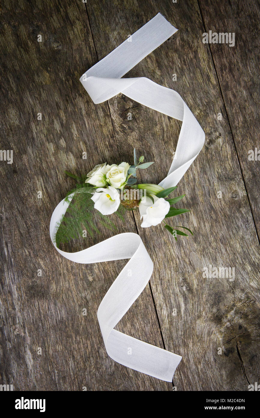 Corsage with white ribbon on wooden surface, elevated view Stock Photo