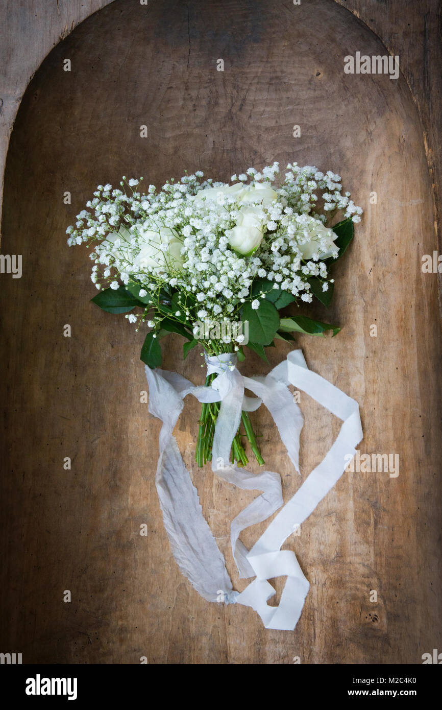 Wedding bouquet tied with white ribbon, on wooden surface Stock Photo